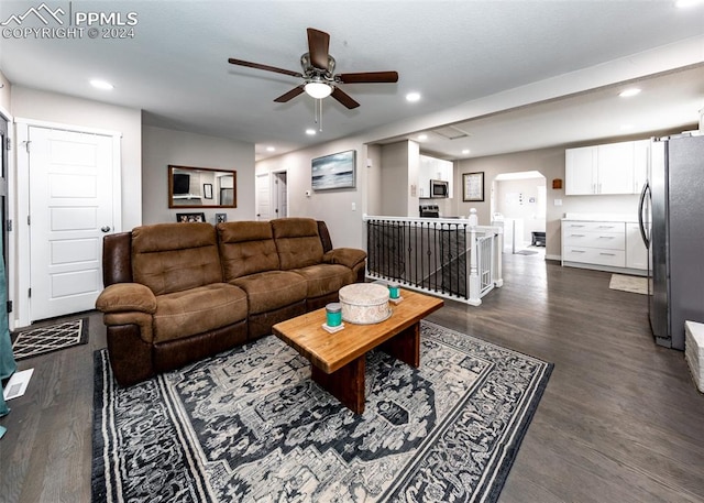 living room featuring ceiling fan and dark wood-type flooring