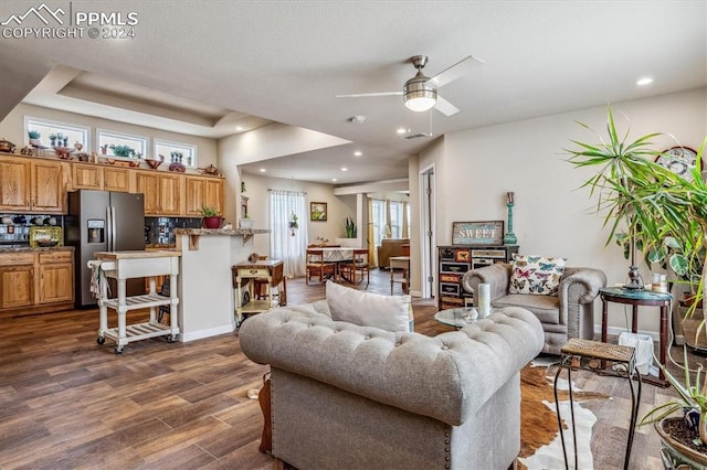 living room with ceiling fan, dark hardwood / wood-style floors, and a tray ceiling