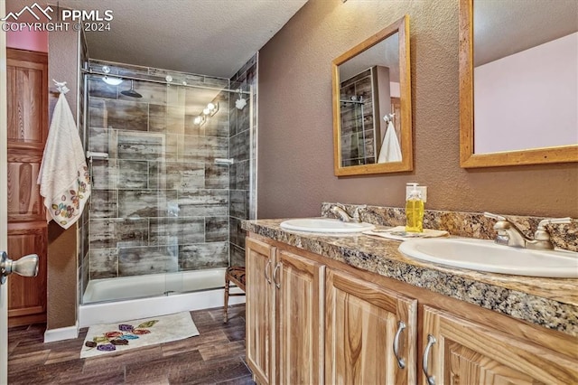 bathroom with vanity, an enclosed shower, and a textured ceiling