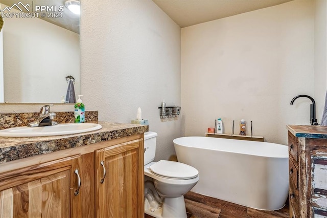 bathroom featuring a tub to relax in, vanity, wood-type flooring, and toilet