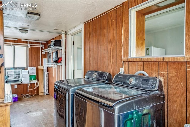 laundry room with wood walls and washing machine and clothes dryer