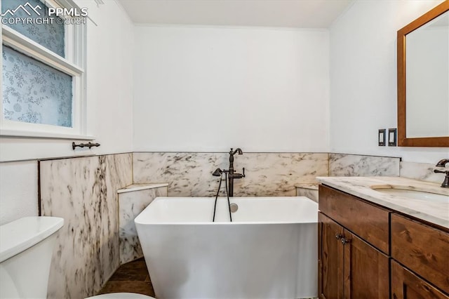 bathroom with a bathing tub, vanity, toilet, and crown molding