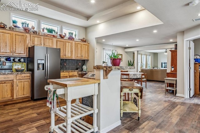 kitchen with decorative backsplash, stainless steel fridge, dark hardwood / wood-style floors, and a breakfast bar