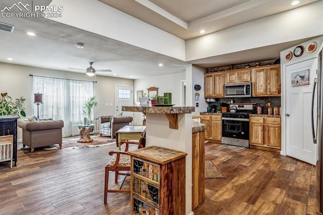 kitchen featuring a kitchen breakfast bar, ceiling fan, decorative backsplash, and appliances with stainless steel finishes