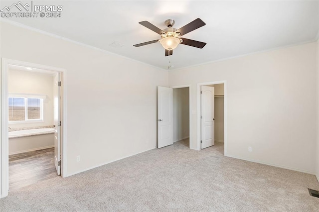 unfurnished bedroom featuring ceiling fan, connected bathroom, ornamental molding, and light colored carpet