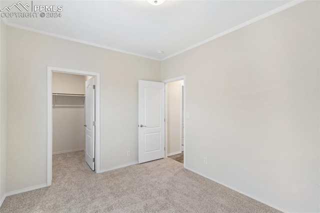 unfurnished bedroom featuring crown molding, a closet, light colored carpet, and a walk in closet