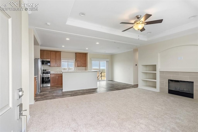 kitchen with stainless steel appliances, a fireplace, ceiling fan, crown molding, and dark colored carpet