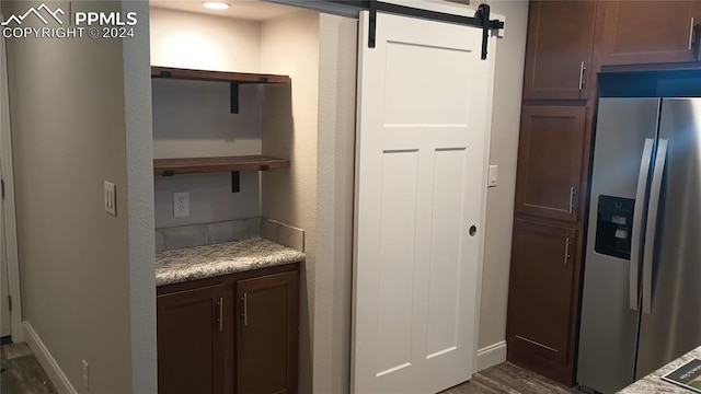 kitchen with dark hardwood / wood-style floors, stainless steel fridge, a barn door, and dark brown cabinets