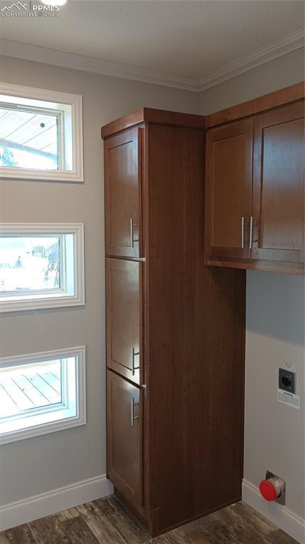 clothes washing area with hookup for an electric dryer, dark hardwood / wood-style flooring, cabinets, and ornamental molding