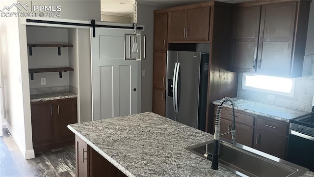 kitchen featuring a barn door, light stone countertops, sink, and appliances with stainless steel finishes