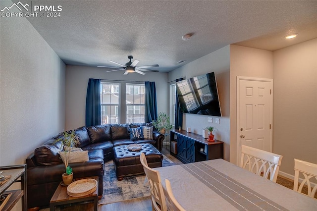 living room featuring ceiling fan, a textured ceiling, and dark hardwood / wood-style floors