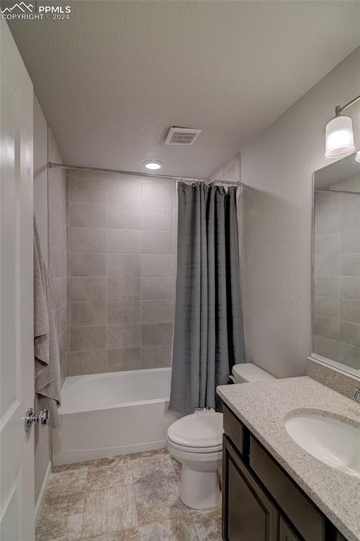 full bathroom featuring tile floors, toilet, vanity, and shower / bath combo with shower curtain