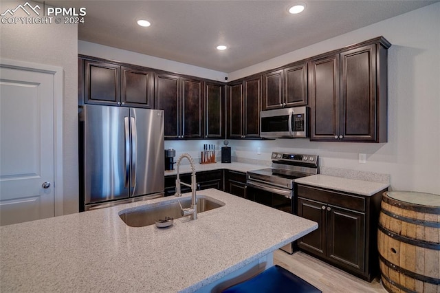 kitchen featuring dark brown cabinets, appliances with stainless steel finishes, light wood-type flooring, and sink