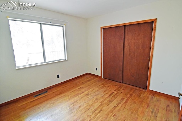 unfurnished bedroom with light wood-type flooring and a closet