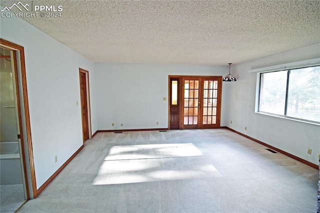 carpeted spare room with french doors and a textured ceiling