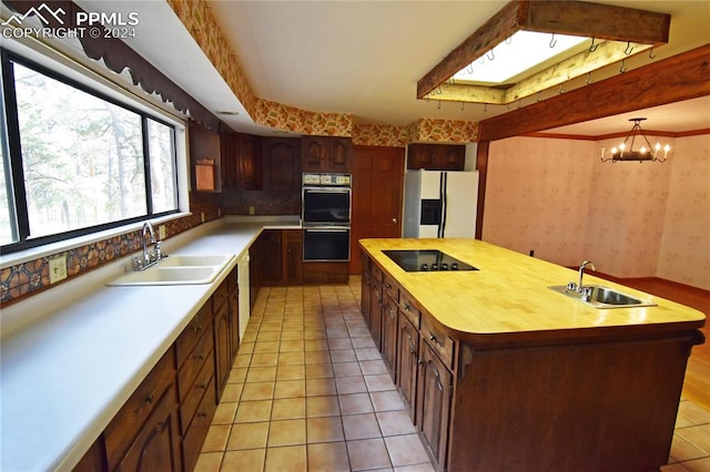 kitchen featuring fridge with ice dispenser, black electric cooktop, a center island with sink, and sink