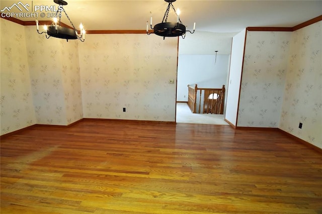 unfurnished room featuring a notable chandelier and light hardwood / wood-style flooring