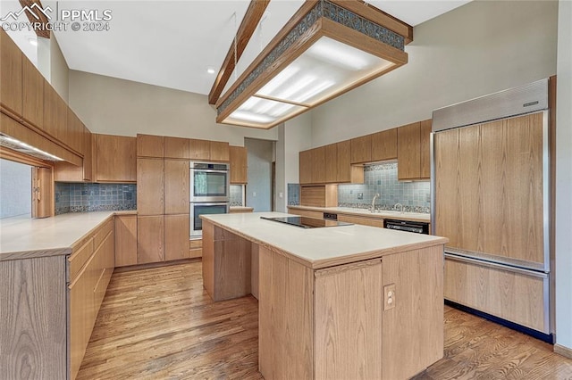 kitchen with a center island, paneled refrigerator, backsplash, and light wood-type flooring