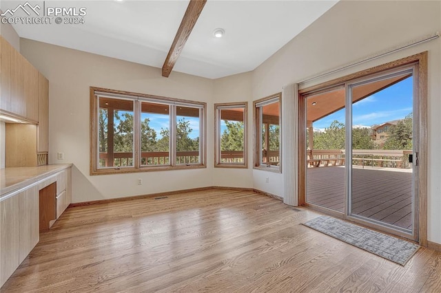 spare room with light hardwood / wood-style flooring and beam ceiling