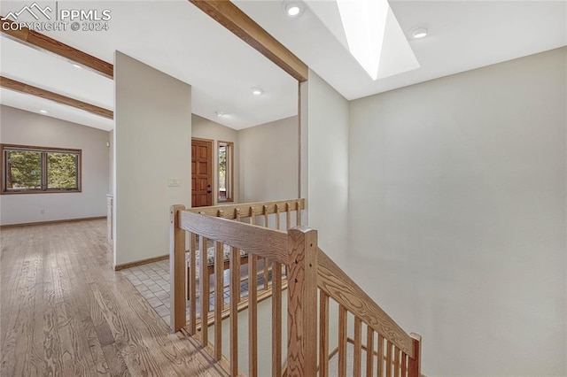 hallway featuring light hardwood / wood-style floors and vaulted ceiling with skylight