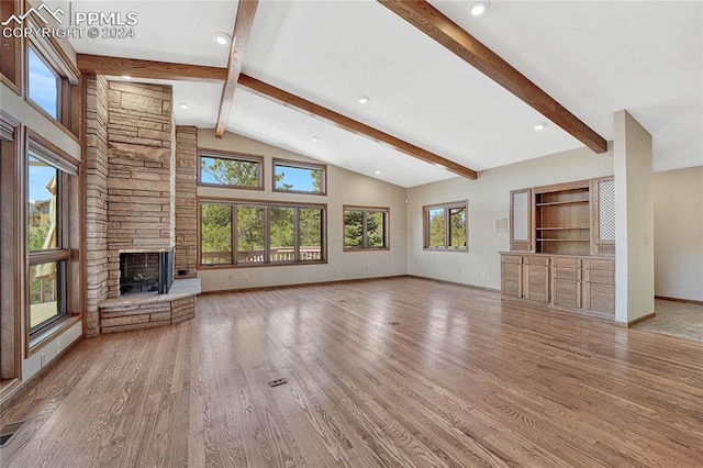 unfurnished living room featuring beamed ceiling, light hardwood / wood-style floors, a stone fireplace, and high vaulted ceiling