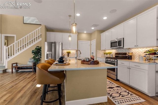 kitchen with appliances with stainless steel finishes, an island with sink, and white cabinets