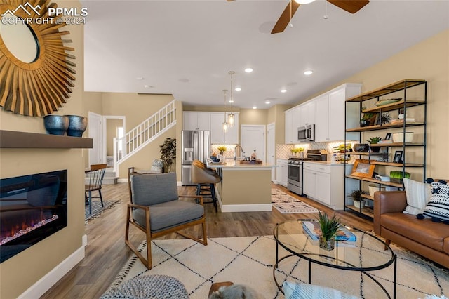 living room with ceiling fan, sink, and light hardwood / wood-style flooring