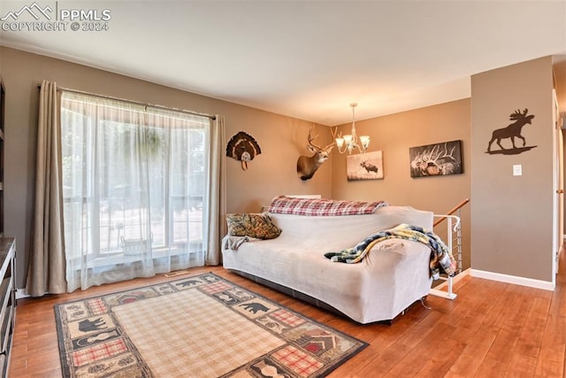 bedroom featuring wood-type flooring, an inviting chandelier, and multiple windows