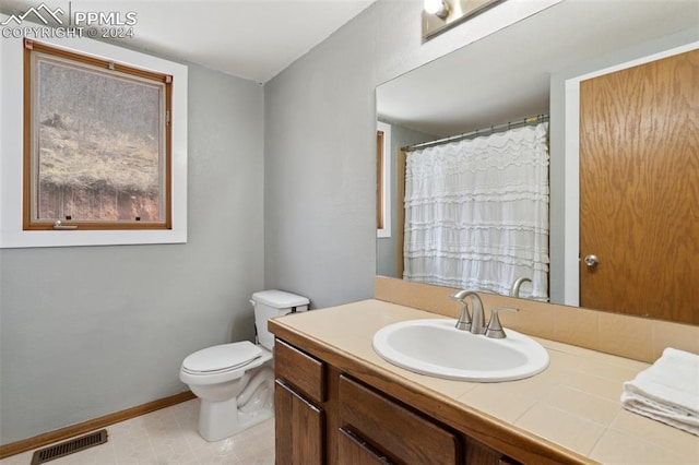 bathroom with tile floors, vanity with extensive cabinet space, and toilet