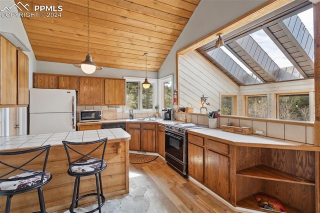 kitchen with hanging light fixtures, light wood-type flooring, white refrigerator, a skylight, and electric range