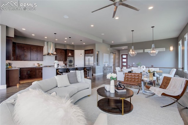 living room featuring ceiling fan with notable chandelier and light hardwood / wood-style flooring