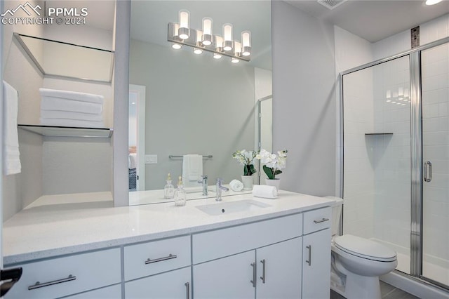 bathroom with vanity, toilet, and a shower with door