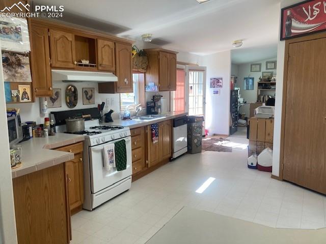 kitchen with sink, white appliances, and light tile flooring