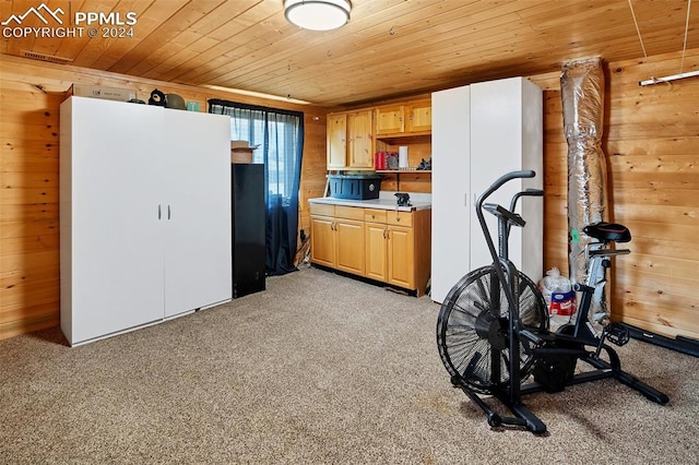 exercise room with wood ceiling, wood walls, and light colored carpet