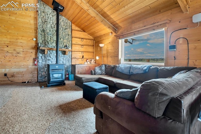 living room with wood walls, vaulted ceiling with beams, wooden ceiling, a wood stove, and carpet