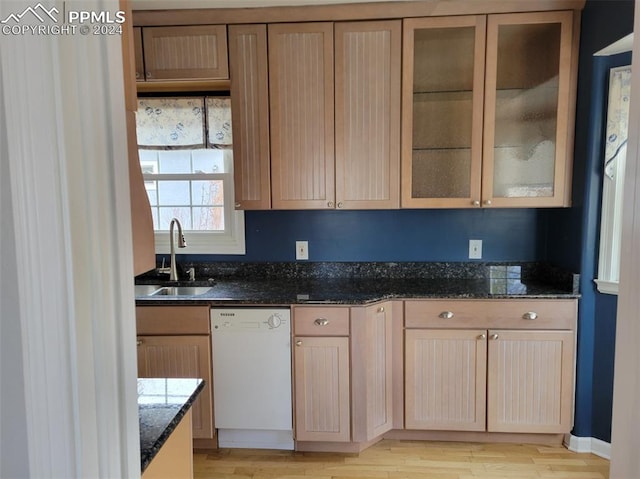 kitchen featuring sink, dishwasher, light hardwood / wood-style floors, and dark stone counters