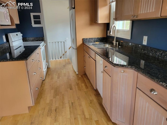 kitchen featuring sink, light wood-type flooring, white appliances, and dark stone counters