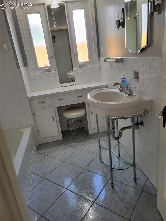 bathroom featuring toilet, a tub, tile patterned flooring, sink, and tasteful backsplash