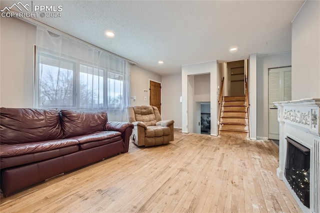 living room featuring a textured ceiling, light hardwood / wood-style flooring, and ornamental molding