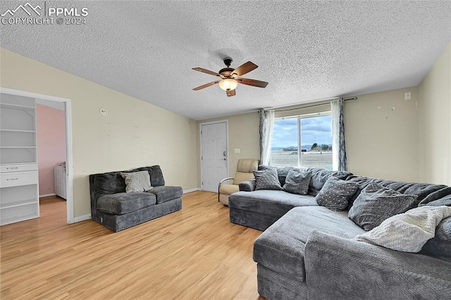 living room with light hardwood / wood-style floors, ceiling fan, and a textured ceiling