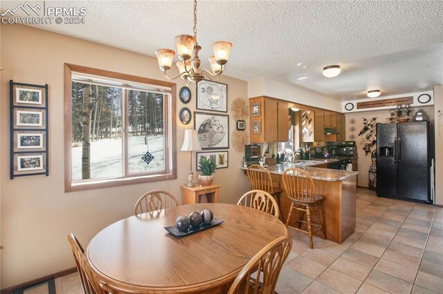 dining space featuring a textured ceiling, an inviting chandelier, and light tile flooring