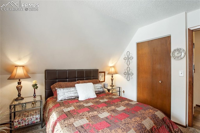 carpeted bedroom with a textured ceiling and vaulted ceiling