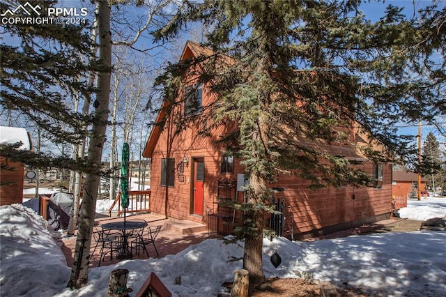 view of snow covered exterior featuring a garage and an outdoor structure