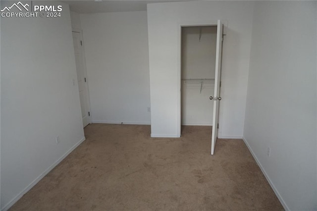 unfurnished bedroom with light colored carpet and a closet