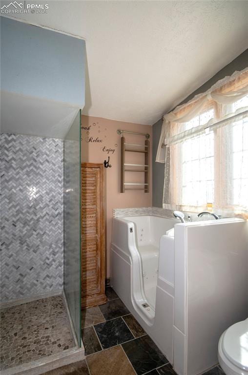 bathroom featuring a tile shower and toilet