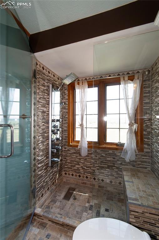 bathroom featuring walk in shower and beamed ceiling