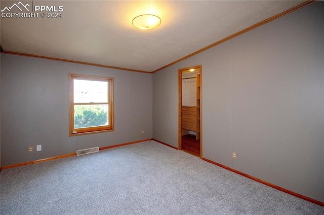 unfurnished room with vaulted ceiling, crown molding, and carpet