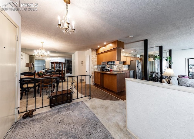 kitchen featuring a notable chandelier, carpet flooring, stainless steel appliances, and a textured ceiling