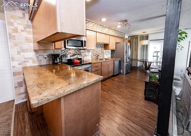 kitchen featuring light stone countertops, stainless steel appliances, dark hardwood / wood-style floors, a textured ceiling, and rail lighting