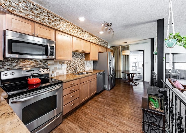 kitchen featuring dark hardwood / wood-style floors, rail lighting, appliances with stainless steel finishes, sink, and a textured ceiling